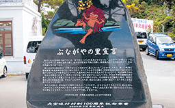 石碑に赤い髪色をしたぶながやのイラストが描かれ、下部に「ぶながやの里宣言」の文字と説明書きが彫られている写真