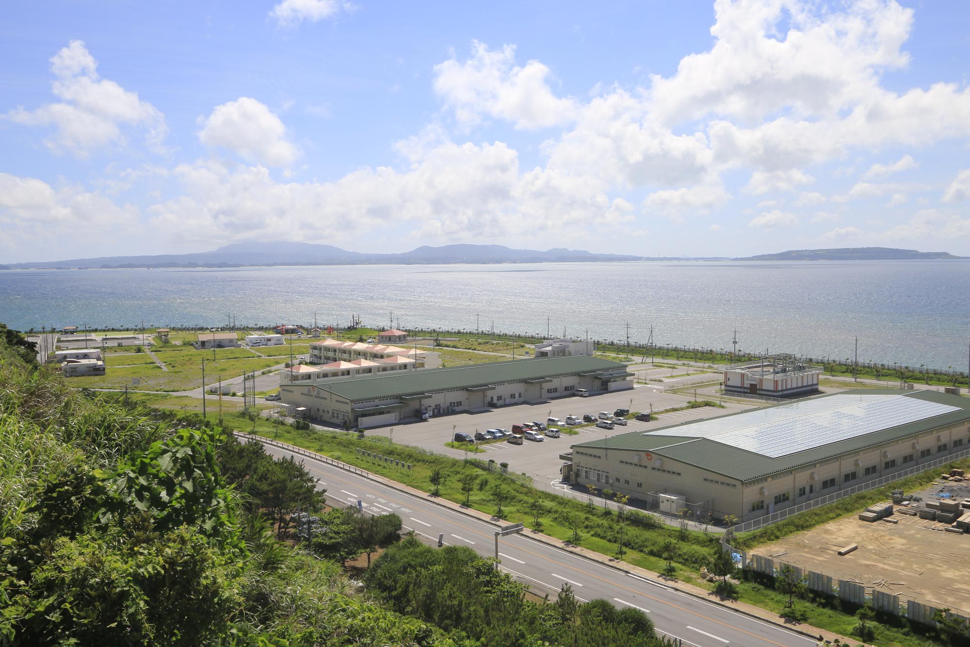 敷地の奥に海と島が広がり、工場が2棟建っている企業支援賃貸工場を上空から見た写真